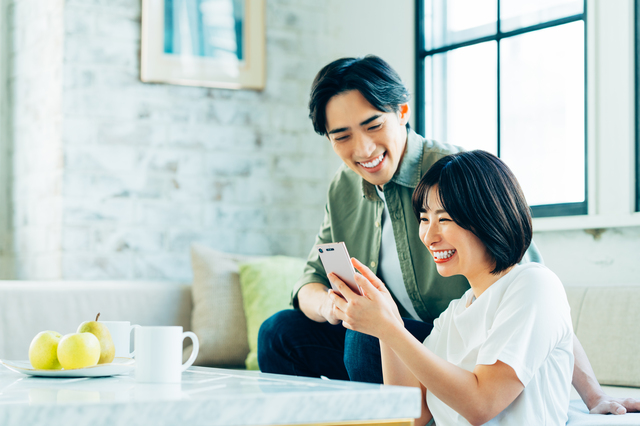 リビングでスマホを見る若い夫婦